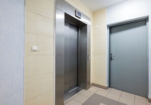Ein Aufzug und eine Tür in einer Diele mit gefliesten Wänden und Boden.