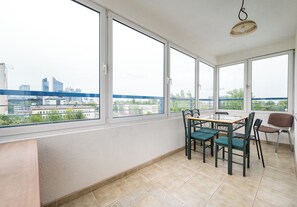 Ein Balkon mit Tisch und Stühlen, großen Fenstern und einer hängenden Lampe.