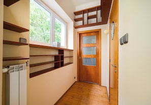 Ein Flur mit Holzboden, einer Holztür mit Fenster und eingebauten Regalen.