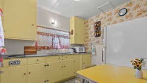 A kitchen with yellow cabinets, a microwave, a sink, and a clock on the wall. - Sierra cabin for two with a cheerful retro kitchen, minutes from Topaz Lake (Coleville)