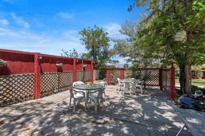 A patio with tables and chairs, a wooden fence, and trees. - Comfortable cabin for two with full kitchen and a freshly updated bathroom, near Topaz Lake (Coleville)