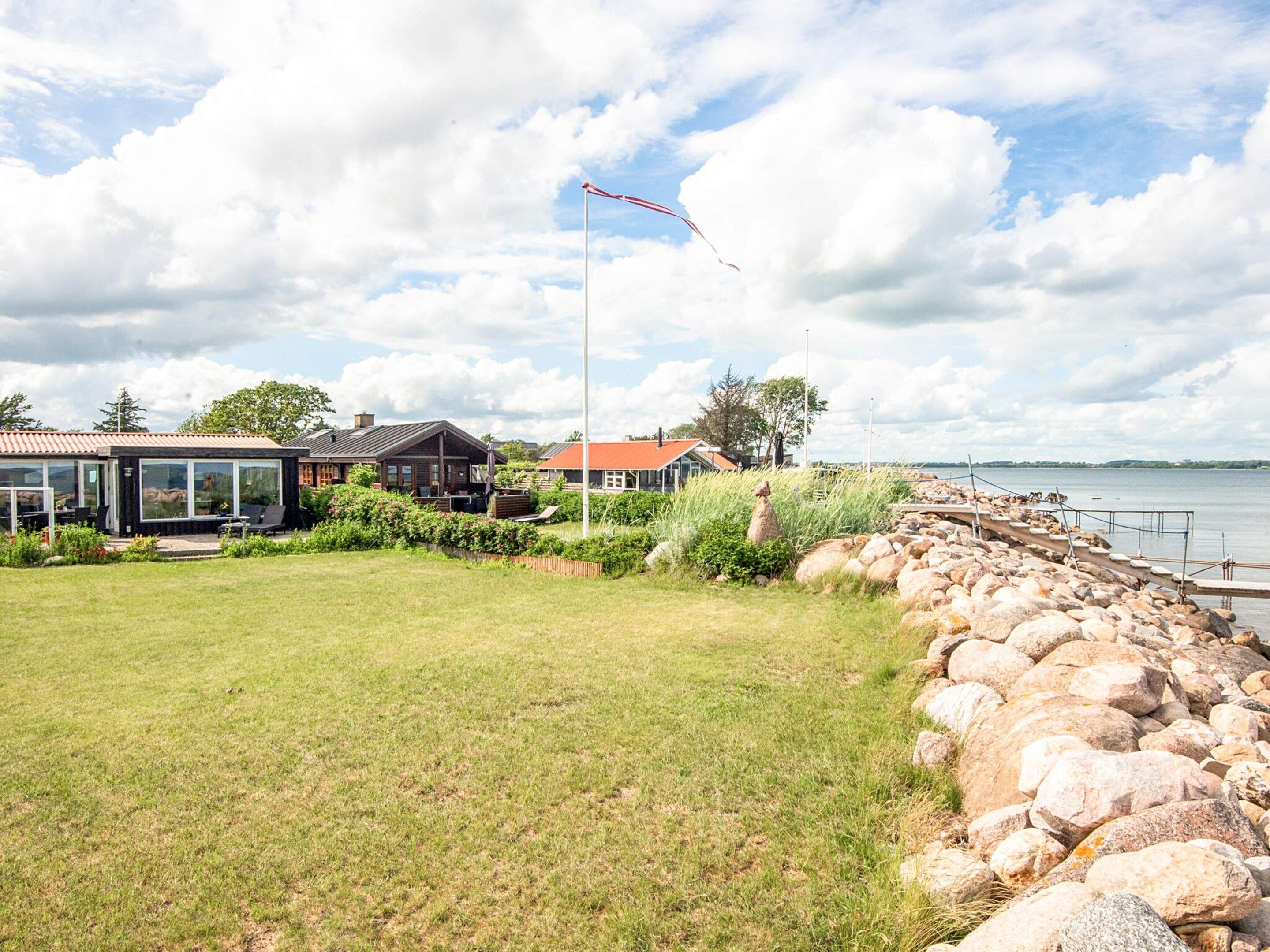 A coastal property with a grassy lawn, a stone wall, and a view of the sea.