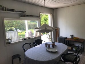 A dining area with a round table, chairs, a window with curtains, a hanging light fixture, and a view of the outdoors. - 4 Star Holiday Home in Frederiksvaerk (Frederiksvaerk)