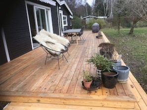 A wooden deck with outdoor furniture, potted plants, and a grill. - 4 Star Holiday Home in Frederiksvaerk (Frederiksvaerk)
