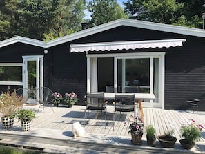 A modern black house with a wooden deck, two chairs, a table, and potted plants. - 4 Star Holiday Home in Frederiksvaerk (Frederiksvaerk)