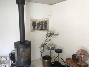A room with a wood-burning stove, a drum set, a fan, and a framed artwork on the wall. - 4 Star Holiday Home in Frederiksvaerk (Frederiksvaerk)