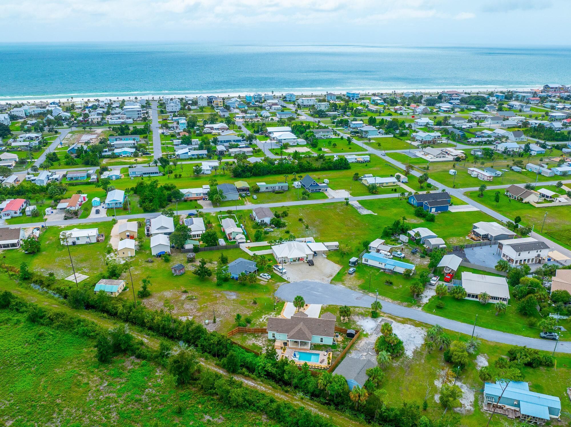 Une zone résidentielle côtière avec des maisons, des routes et une plage en arrière-plan.