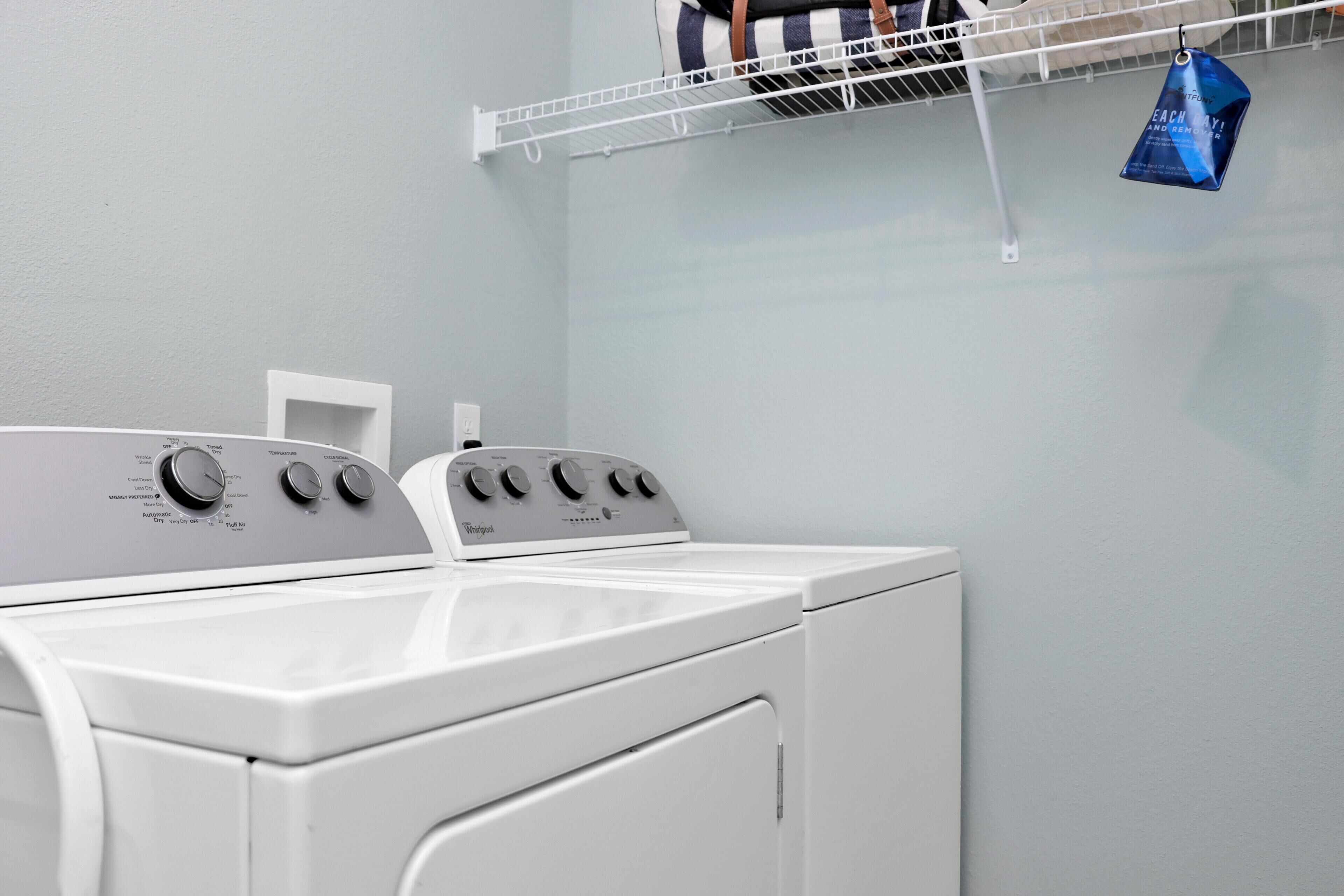 A laundry area with two front-loading washing machines and a drying rack.