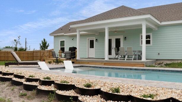Una casa con piscina, terraza techada y mobiliario exterior.