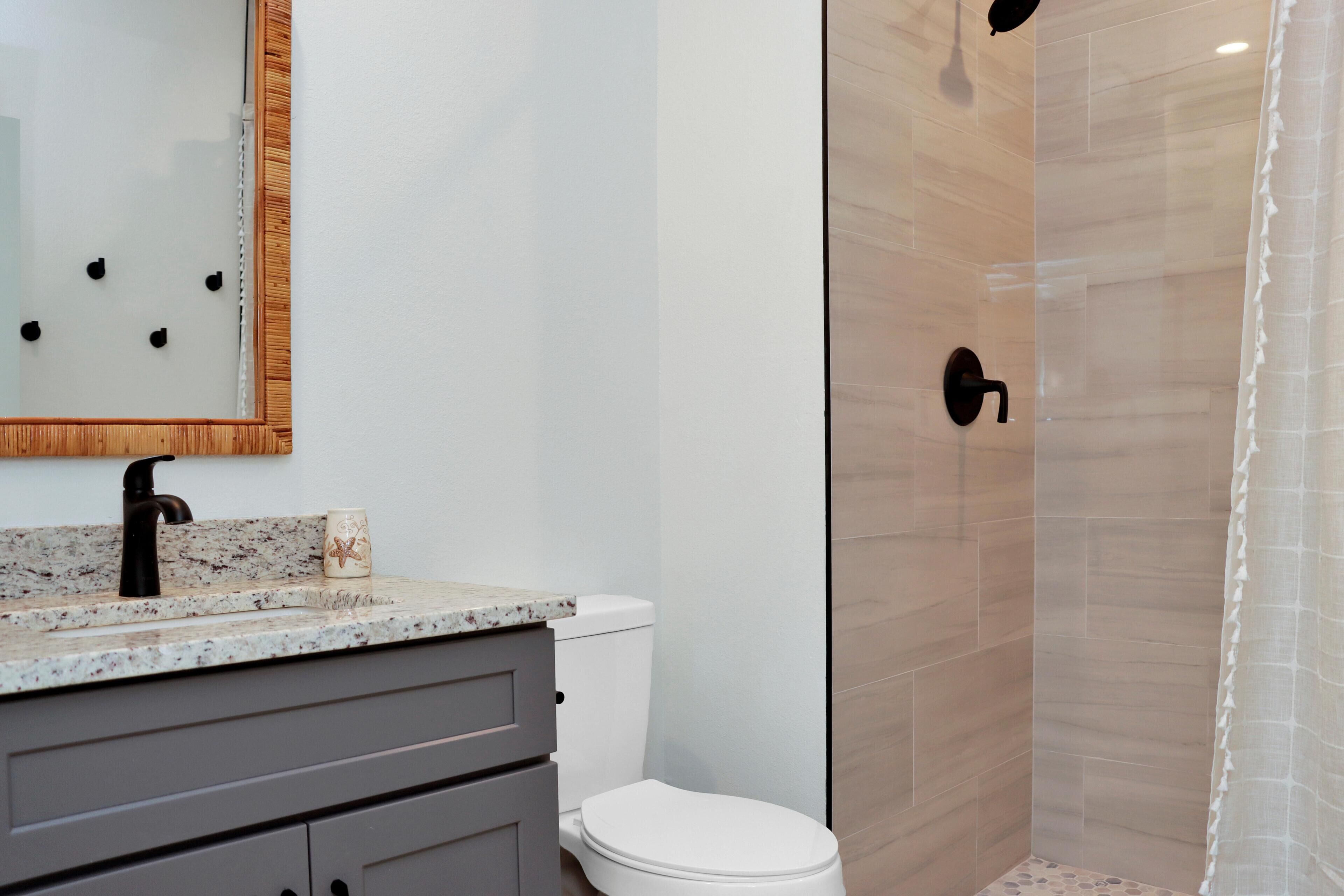 Ein Badezimmer mit Toilette, Waschbecken, Spiegel und Dusche.