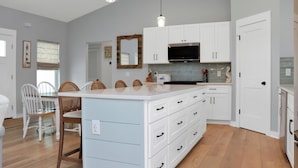Una cocina moderna con armarios blancos, una isla grande e iluminación colgante.