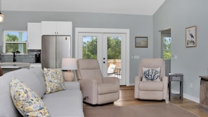 Una sala de estar moderna con un sofá gris, sillones color beige y un comedor.
