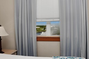 Ein Zimmer mit einem Bett, einer Lampe und einem fensterbehangenen Fenster.