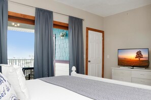 Un dormitorio con cama, televisión, puerta y vistas al exterior.