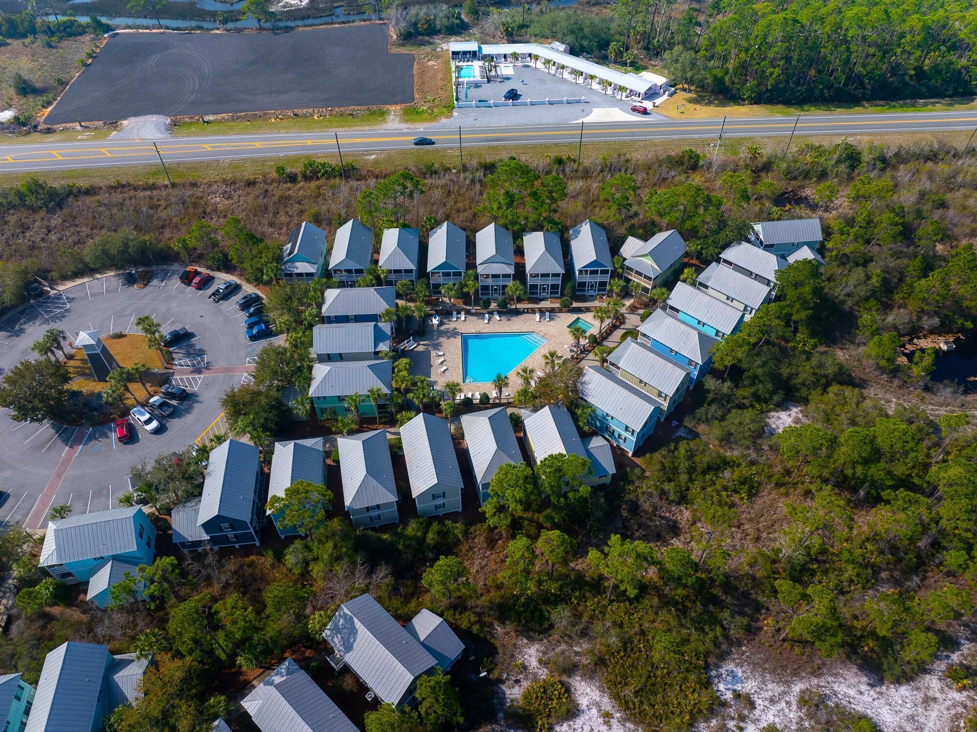 An aerial view of a resort with multiple blue-roofed buildings, a swimming pool, and a parking area.