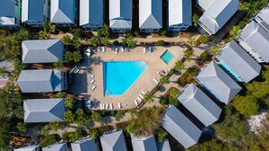 An aerial view of a resort with multiple buildings, a central swimming pool, and surrounding palm trees. - Barefoot Cottage B28 (Port St. Joe)