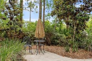 Un patio ajardinado con una mesa y sillas, rodeado de árboles y vegetación.