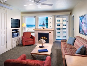 Ein Wohnzimmer mit Kamin, Fernseher und Blick auf den Strand.