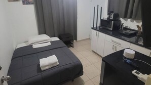 Ein Hotelzimmer mit einem Bett, einem kleinen Schreibtisch, einer Mikrowelle und einem Schrank.
