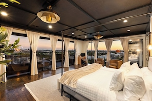 Une chambre moderne avec un grand lit, un bureau et une vue sur le paysage urbain.
