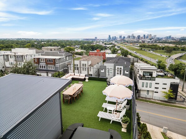 A residential area with modern houses, a green lawn, and a city skyline in the background.