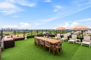 Una terrazza sul tetto con tavolo, sedie e zone relax.