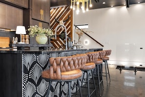 A modern kitchen with a bar area featuring tufted bar stools and a decorative backsplash. - Skyline Luxury, Rooftop Experience, Villa Sophia Nashville (Nashville)