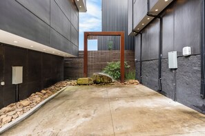 A modern building with a concrete pathway, a wooden structure, and a small water feature. - Skyline Luxury | Rooftop Experience | Villa Sophia (Nashville)