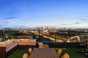An outdoor seating area with a city skyline view, including a prominent tower. - Skyline Luxury | Rooftop Experience | Villa Sophia (Nashville)