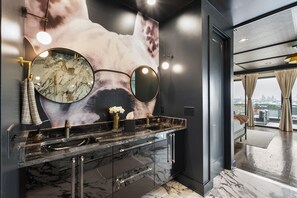 Une salle de bain moderne avec un grand miroir, un comptoir en marbre et une vue sur la ville par la fenêtre.