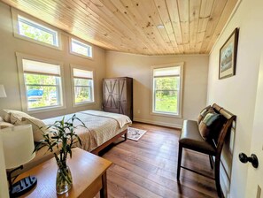 A bedroom with a wooden ceiling, a bed, a desk, a chair, and a wardrobe. - New Garden Retreat w/ Fire Pit, 5 Min to Town (Ellsworth)