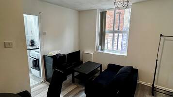 A compact living space with a dining area, a sofa, a small table, and a window with a view of a brick building.