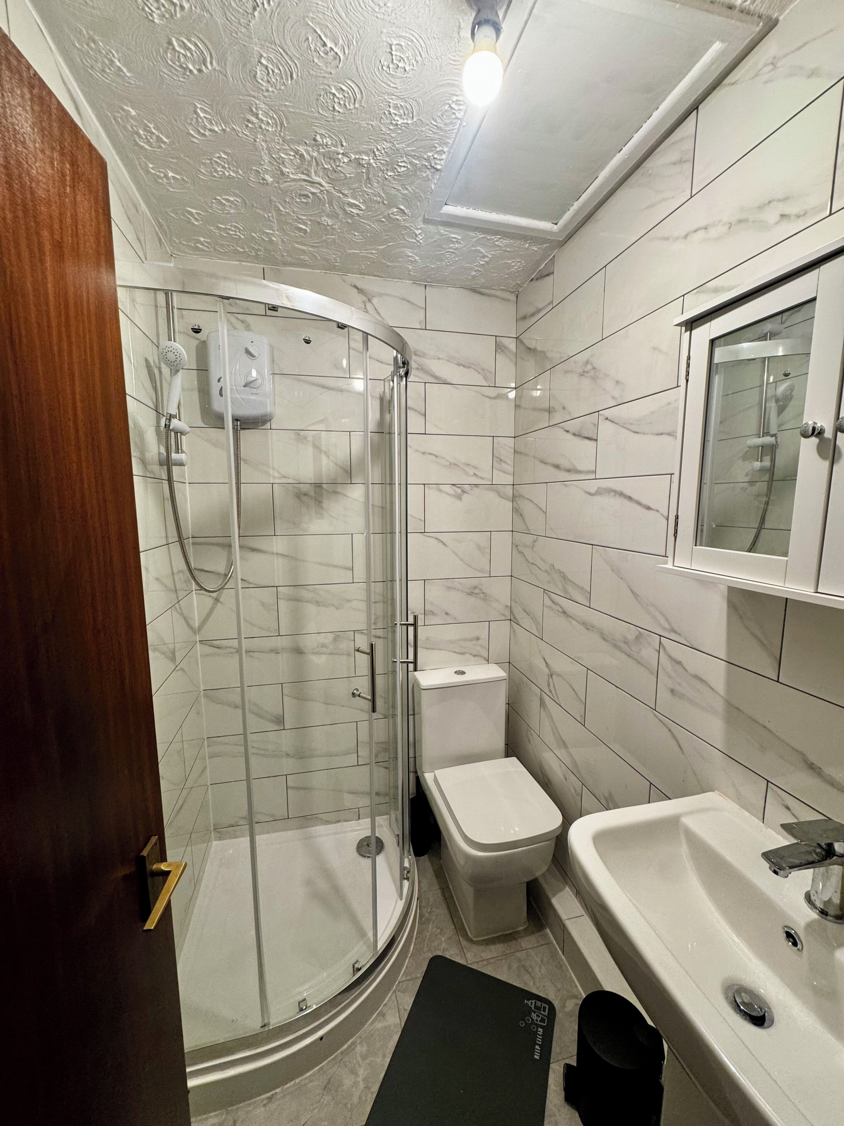 A bathroom with a shower, toilet, and sink.