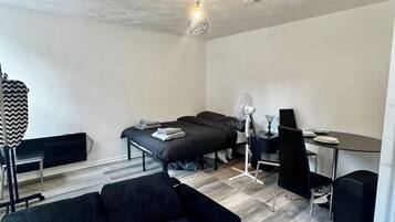 A modern, compact room with a sofa, a bed, a desk, and a dining table.