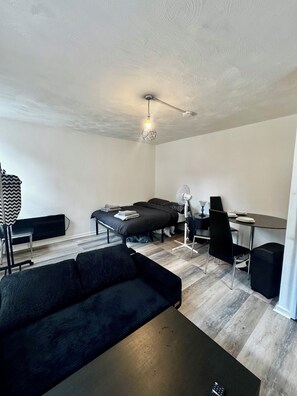 A modern, compact room with a sofa, a bed, a desk, and a dining table. - Stylish Studio In Manchester City Centre - Sleeps 3 (Manchester)