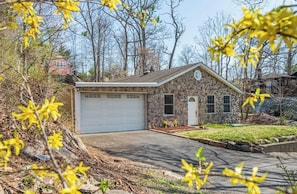 A stone house with a garage, surrounded by trees and a grassy yard. - Cozy Ranch Steps from the Lake. (Andover)