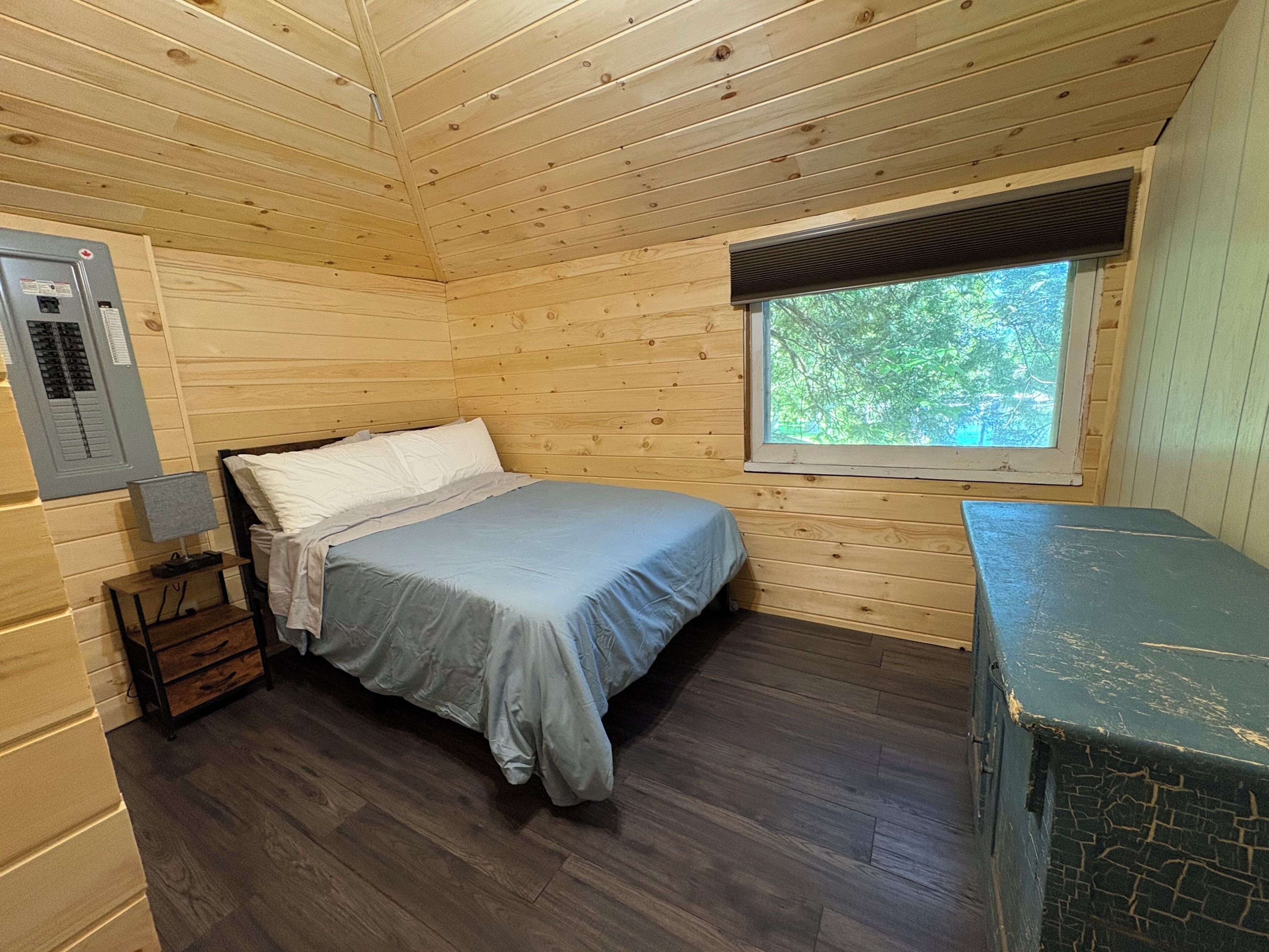 Ein Zimmer in einer Holzhütte mit Bett, Fenster und Heizung.