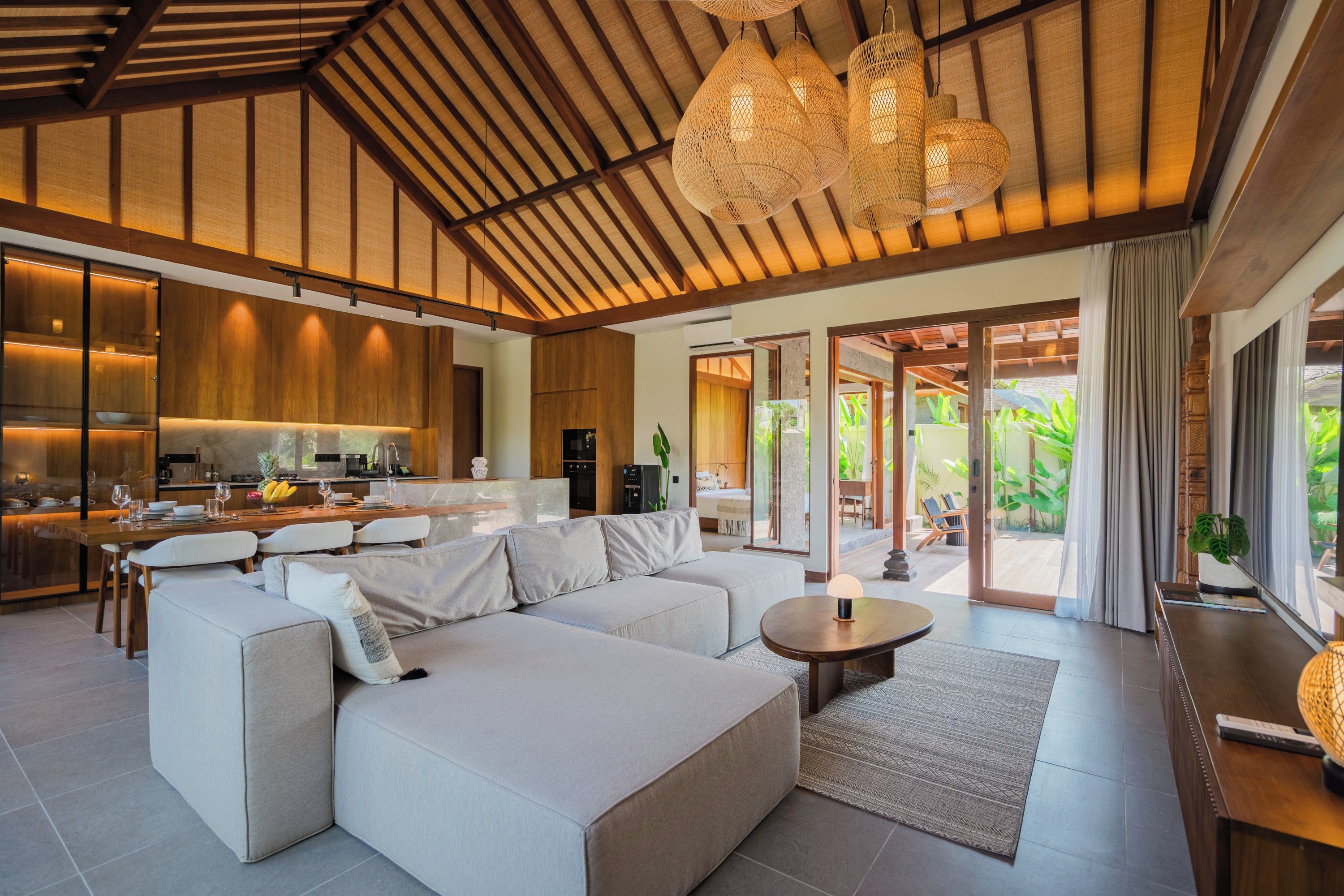 A modern living area with a large sofa, a dining table, and a kitchen in the background.