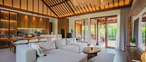 Un espace de vie moderne comprenant un grand canapé, une table à manger et une cuisine en arrière-plan.
