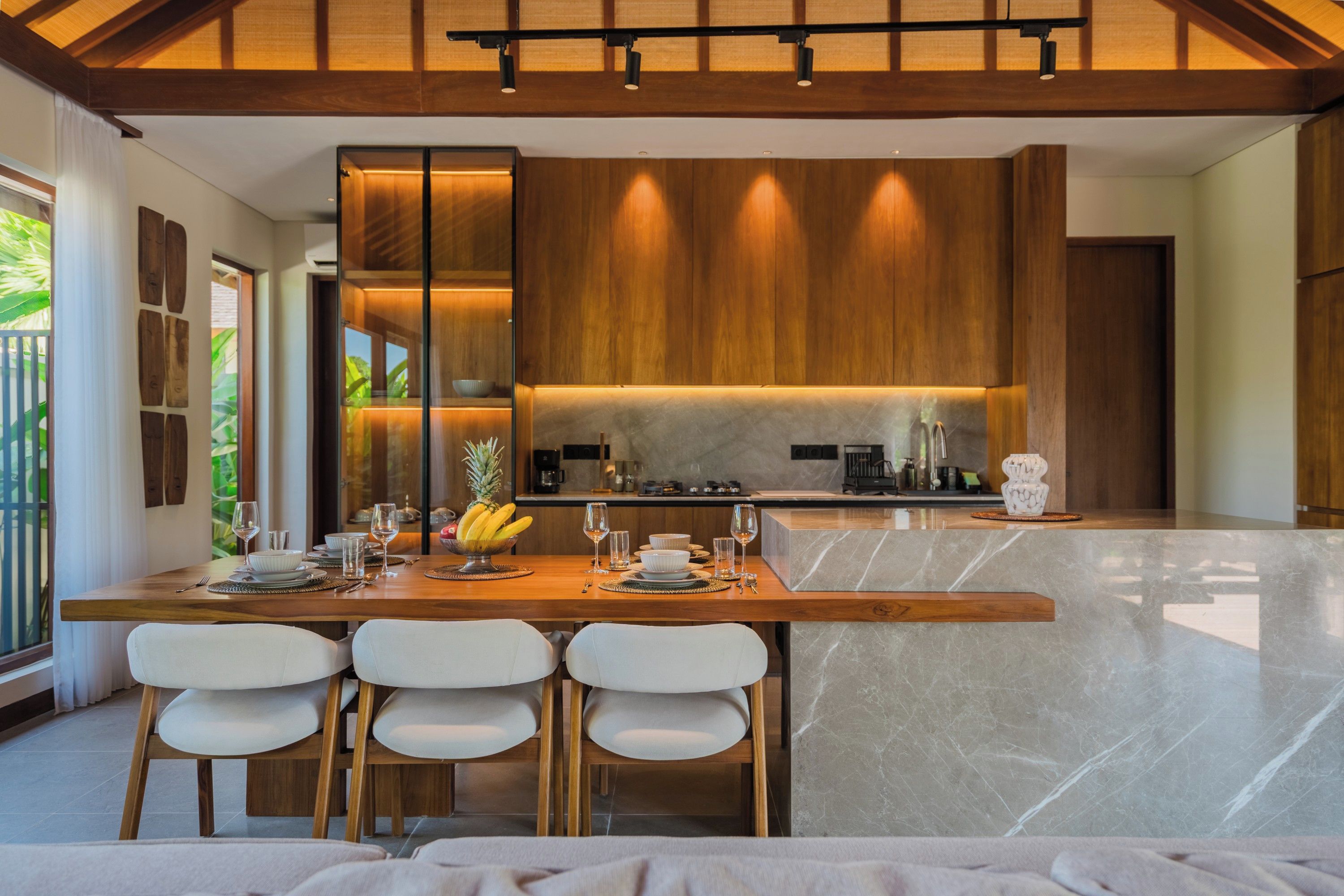 A modern kitchen with a central island, bar stools, and a dining area with a wooden table and chairs.