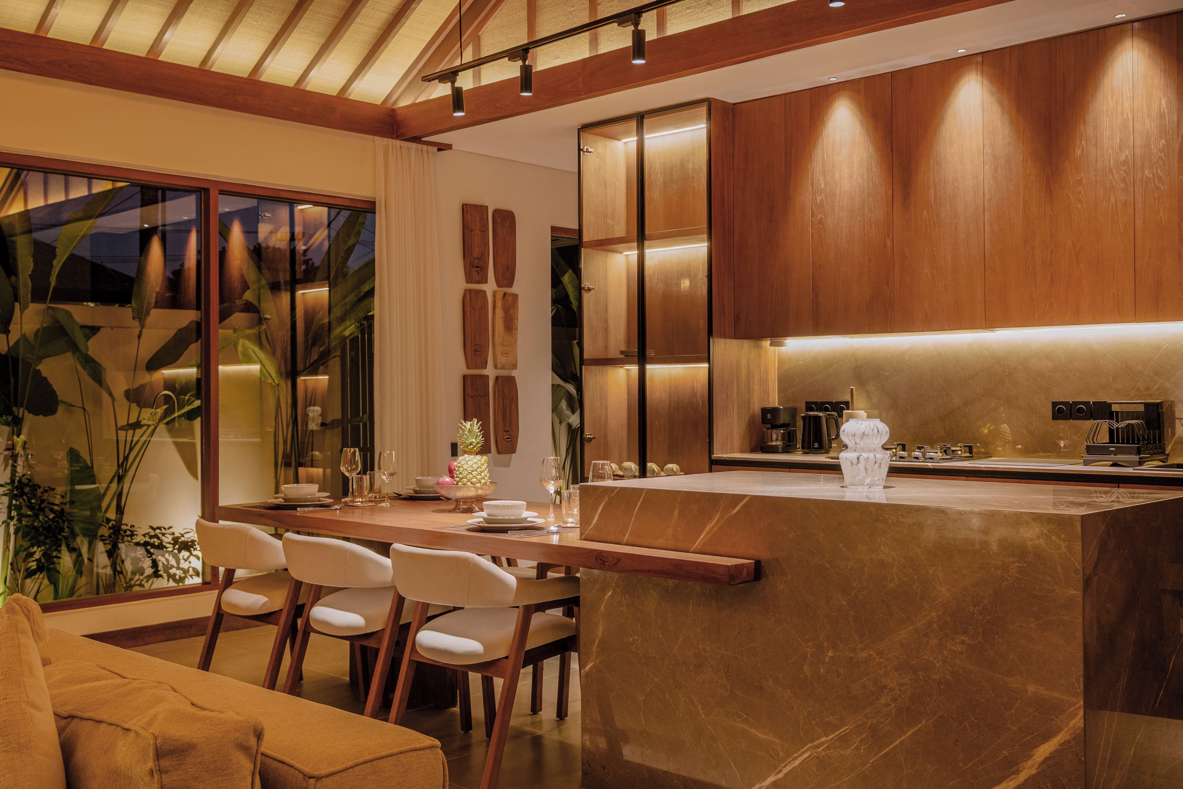 A modern kitchen with a marble countertop, wooden cabinets, and a dining area with a sofa and chairs.