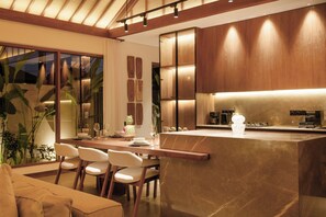 A modern kitchen with a central island, wooden cabinets, and a dining area with chairs. - Apura Panoramic Villa 2BD Ubud (Ubud)