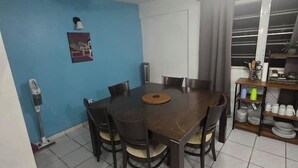 Een eethoek met een tafel, stoelen, een plafondventilator en een raam met gordijnen.