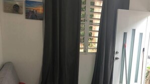 Ein Zimmer mit einem grauen Sofa, roten Kissen, einem kleinen schwarzen Tisch und einem grünen Eimer.