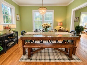 A dining room with a wooden table, benches, and a plaid rug.