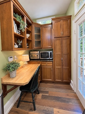 A kitchen with wooden cabinets, a countertop, a stove, a microwave, and a potted plant. - 1917 Bristol Tudor, Sleeps 10, Minutes to Downtown, BMS Speedway & Holston River (Bristol)