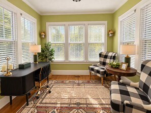 A room with a checkered armchair, a desk with a lamp, and a window with blinds. - 1917 Bristol Tudor, Sleeps 10, Minutes to Downtown, BMS Speedway & Holston River (Bristol)