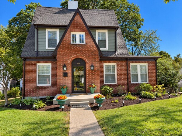 A two-story house with a brick facade, a central entrance with a door, and a small front porch.