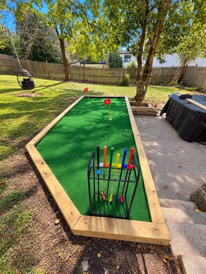 A miniature golf course with a green artificial turf, numbered holes, and a rack of colorful golf balls. - 1917 Bristol Tudor, Sleeps 10, Minutes to Downtown, BMS Speedway & Holston River (Bristol)