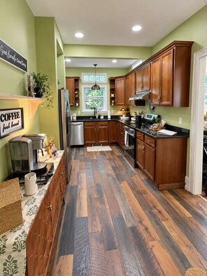 A kitchen with wooden cabinets, a stainless steel refrigerator, and a coffee station.